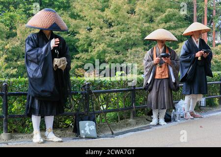 Kyoto, Giappone - 23 novembre 2007: I monaci buddisti Zen praticano il takuhatsu in abiti tradizionali e cappelli di paglia. Scambiò canti di sutra per donat Foto Stock