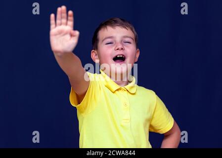 Giovane caucasico a bocca aperta 9 s ragazzo mettendo la mano fuori facendo segno di stop Gesture.Blue sfondo studio. Foto Stock