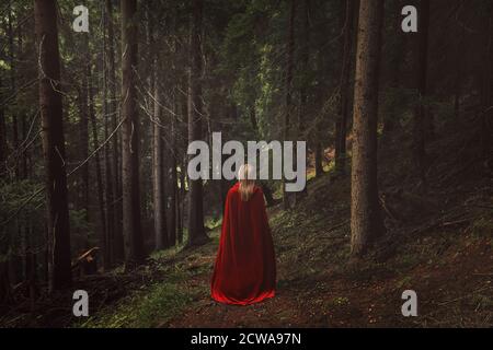 Donna con mantello rosso in una foresta di fata Foto Stock