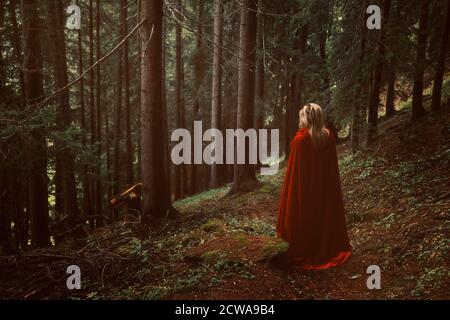 Donna con mantello rosso in una foresta misteriosa Foto Stock