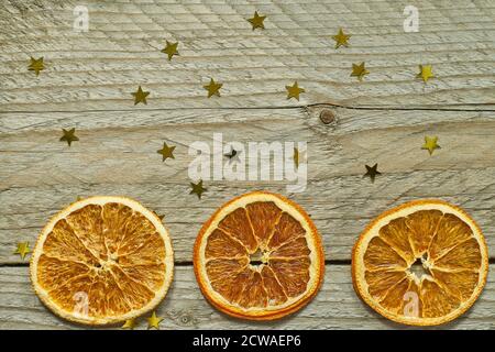 Sfondo in legno d'epoca con corona di Natale - fette aranciate e confetti d'oro in pelo di stella. Vista dall'alto con spazio per la copia Foto Stock