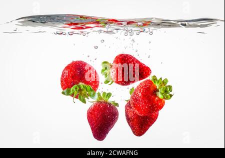 Fragole mature galleggianti in acqua dopo la caduta Foto Stock