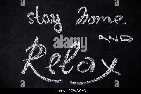 Concetto del periodo di isolamento di quarantena di rimanere a casa. Lavagna con scritte in gesso scritte a mano, rimani a casa e rilassati. Foto Stock
