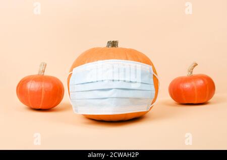 La zucca di Halloween arancione indossa una maschera medica protettiva. Concetto Covid-19. Foto Stock