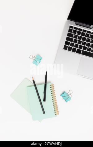 Vista dall'alto dell'area di lavoro bianca con computer portatile e cancelleria. Concetto minimalista. Foto Stock