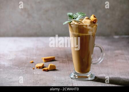 Caffè espresso latte alla moda con caffè espresso alla crema di caffè espresso in vetro alto, decorato da caramelle e menta dalgona. Grigio concer Foto Stock