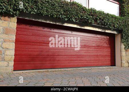 Porta rossa del garage di alta qualità (porta sezionale) vicino ad un edificio residenziale Foto Stock