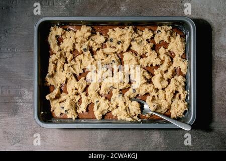 Pronti a cuocere i tipi di pasta di cioccolato e shortbread per la cottura a casa tendenza dessert brownie e biscotti in vassoio da forno su tela di lino ov Foto Stock