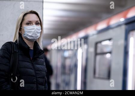 Mosca. Russia. 28 settembre 2020 UNA giovane donna che indossa una maschera medica protettiva si trova sulla piattaforma di una stazione della metropolitana, in attesa di salire a bordo Foto Stock