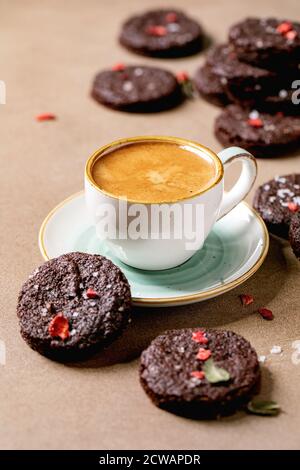 Biscotti salati di brownie al cioccolato fondente fatti in casa decorati da lamponi freschi e secchi, serviti con scaglie di sale, bacche, menta e tazza di caffè Foto Stock