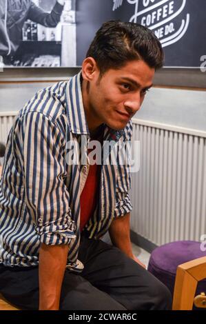 Ragazzi indiani che danno le pose per scattare foto di moda in studio con l'uso di specifiche, cuffie, lampade props. Foto Stock