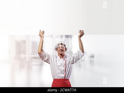 Giovane chef maschile con un cartello bianco vuoto Foto Stock