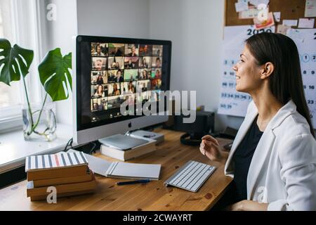 Bella giovane donna con zoom videoconferenza chiamata via computer. Zoom riunione chiamata. Ufficio domestico. Soggiorno a casa e lavoro da casa Concept Covid-19 Foto Stock