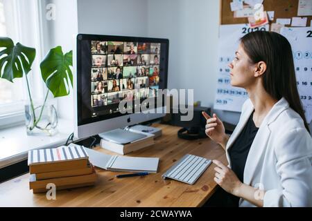 Bella giovane donna con zoom videoconferenza chiamata via computer. Zoom riunione chiamata. Ufficio domestico. Soggiorno a casa e lavoro da casa Concept Covid-19 Foto Stock