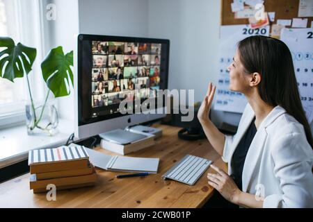 Bella giovane donna con zoom videoconferenza chiamata via computer. Zoom riunione chiamata. Ufficio domestico. Soggiorno a casa e lavoro da casa Concept Covid-19 Foto Stock