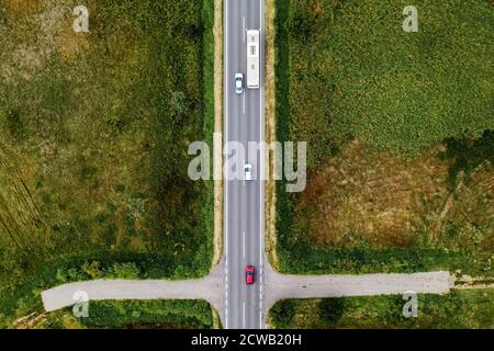 Vista aerea di tre auto e autobus passeggeri sulla strada, vista dall'alto dal drone pov Foto Stock