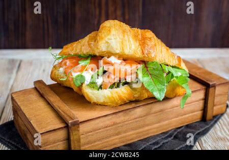 Delizioso croissant alle calorie con salmone, formaggio di cagliata ed erbe aromatiche. Foto Stock