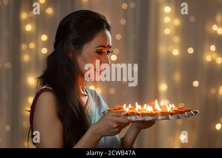 Donna che guarda un piatto decorato con diya Foto Stock