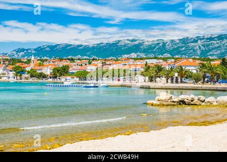 Lungomare e spiaggia nella città di Novalja sull'isola di Pag, Croazia, mare turchese in primo piano Foto Stock