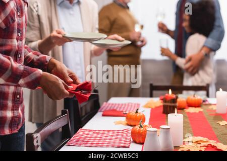 Fuoco selettivo delle donne multietniche che servono il tavolo con le decorazioni di ringraziamento Foto Stock