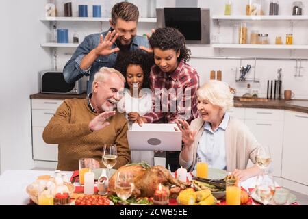 Fuoco selettivo della famiglia multietnica che ha videochiamata sul laptop durante il ringraziamento Foto Stock