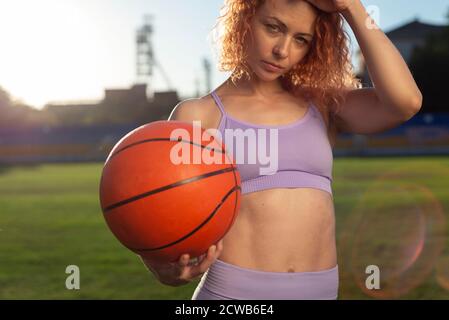 ragazza atleta giocatore di bietball, tenendo una palla di bietball in mano, sullo sfondo del sole che tramonta. All'aperto competitivo giocatore di basket h Foto Stock