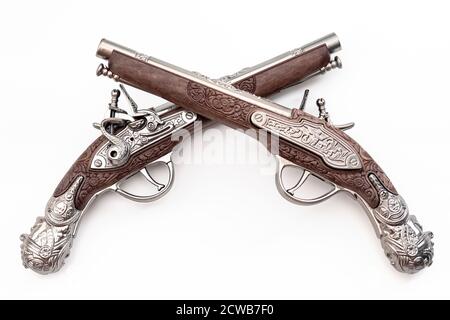 Armi da fuoco risalente alla rivoluzione americana e antico concetto di collezionismo con le pistole ornate in flintlock duellanti di vecchio stile incrociate nel duello isola Foto Stock