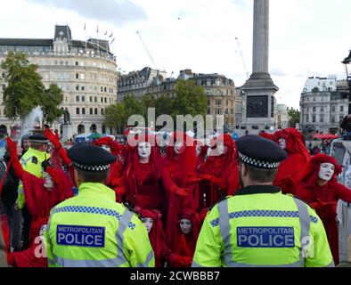 Il Circo invisibile alla ribellione estinzione protesta il 13 ottobre 2019, a Trafalgar Square nel centro di Londra . Il gruppo Invisible Circus di Bristol è composto da artisti di strada vestiti con abiti rossi che simboleggiano il sangue che lega l'umanità insieme. Foto Stock