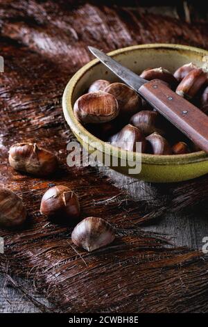 Vaso in ceramica di materie commestibili di castagne con coltello vintage su un tavolo di legno Foto Stock