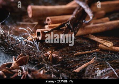 Un mucchio di spezie bastoncini di cannella, bastoncini di vaniglia e stelle di anice sopra la crosta di palma scura. Foto Stock
