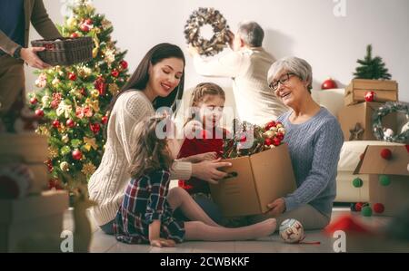 Buon Natale e buone feste! Nonni, madre, padre e bambini decorano l'albero in camera. Famiglia amorevole al chiuso. Foto Stock