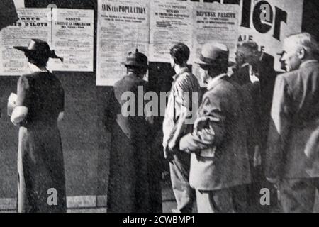 Fotografia in bianco e nero riguardante i primi giorni della guerra a Parigi; persone che leggono poster sulla difesa passiva affissi su un muro. Foto Stock