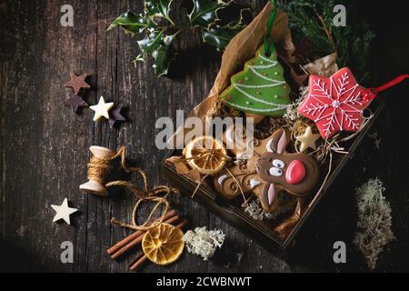 Natale fatti a mano gingerbreads modellato come albero di Natale, la renna Rudolph e forme di fiocco di neve in una scatola di legno sopra il vecchio tavolo in legno e decorate con f Foto Stock
