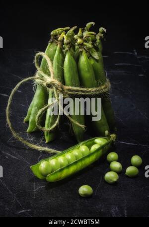 Un pacchetto di piselli freschi su marmo nero Foto Stock