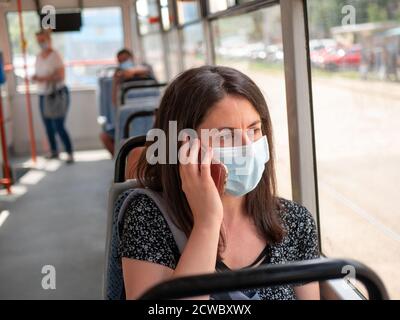 Donna che utilizza i trasporti pubblici indossando la maschera facciale sull'autobus durante la Pandemia di coronavirus di Covid 19, Sofia, Bulgaria Foto Stock