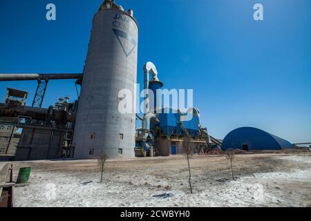 Mynaral/Kazakhstan - Aprile 23 2012: Stabilimento di cemento Jambyl. Edifici di fabbrica e silos. Vista panoramica con obiettivo grandangolare. Cielo blu. Foto Stock