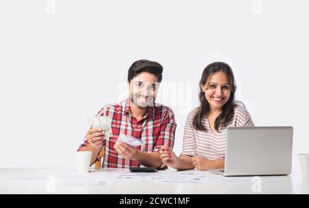 Focalizzato giovane coppia indiana contabilità, il calcolo delle fatture, discutere di bilancio di pianificazione insieme utilizzando online servizi bancari e calcolatrice, il controllo Foto Stock