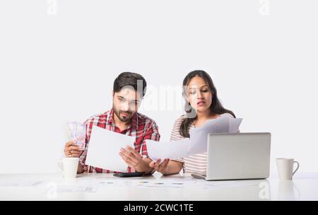 Focalizzato giovane coppia indiana contabilità, il calcolo delle fatture, discutere di bilancio di pianificazione insieme utilizzando online servizi bancari e calcolatrice, il controllo Foto Stock
