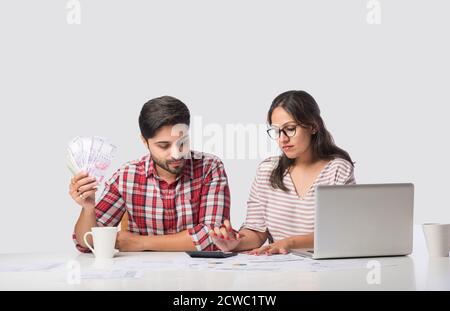 Focalizzato giovane coppia indiana contabilità, il calcolo delle fatture, discutere di bilancio di pianificazione insieme utilizzando online servizi bancari e calcolatrice, il controllo Foto Stock