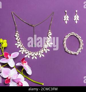 Elegante bracciale e orecchini in oro con diamanti su viola sfondo Foto Stock