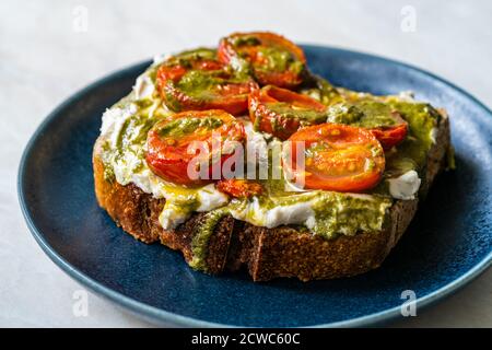 Toast sano tartine con crema di formaggio di formaggio di formaggio di formaggio di formaggio di formaggio di formaggio di formaggio di formaggio aromatizzato, salsa di pesto e pomodori ciliegini. Pronto per alimenti biologici. Foto Stock