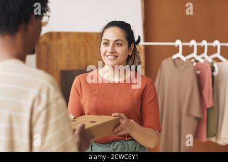 Giovane donna sorridente che dà il pacco imballato all'uomo di consegna lavorano nel servizio di consegna Foto Stock