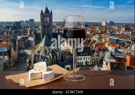 Bicchiere di vino rosso con formaggio brie contro la vista della grande cattedrale di Gand, Belgio Foto Stock