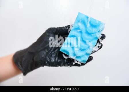 Mano femminile in guanti neri lavaggi finestre. Spugna con schiuma Foto Stock
