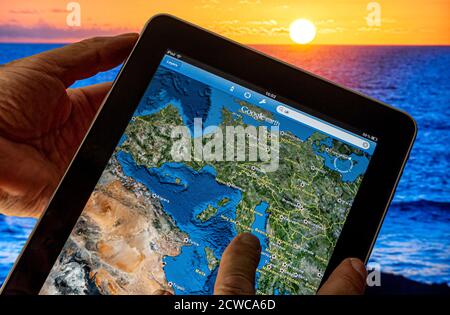 GOOGLE EARTH Apple iPad Smart Tablet computer con applicazione Google Earth su schermo con Europa continentale, Italia Francia Africa ecc, mare e tramonto in background Foto Stock