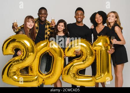 Concetto di celebrazione del nuovo anno 2021. Due tipi attraenti e quattro ragazze belle che ridono con palloncini 2021. Foto Stock