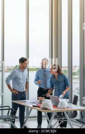 Team di architetti multietnici che lavorano ai piani di costruzione nella sala riunioni. Gli ingegneri discutono sul progetto in ufficio. Foto Stock