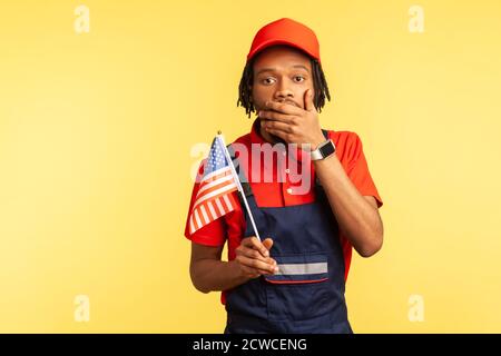 Un pugno afro-americano spaventato in uniforme con tempri che tengono la bandiera degli stati uniti chiudendo la bocca con la mano, violazione dei diritti umani, libertà di parola. Poll Foto Stock