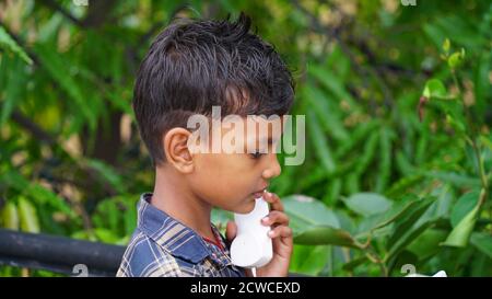 Piccolo ragazzo indiano con telefono che chiama il ricevitore del telefono a casa sul tetto. Foto Stock