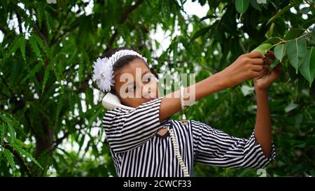 Ragazza indiana intelligente che tiene il ricevitore del telefono in mano e che parla Foto Stock